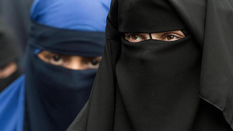 Eine vollverschleierte Frau schaut durch die Schlitze ihres Nikab.