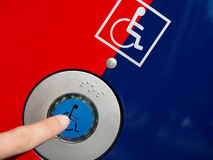 Ein Finger drückt eine Ruftaste für Rollstuhlfahrer auf einer Info-Säule. Foto: picture alliance / dpa/Archivbild