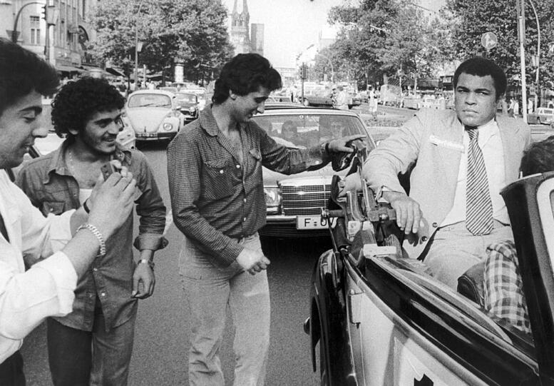 Ali, auf diesem Foto bei einem Besuch in Berlin, war nun gezwungen, wieder von vorne anzufangen und sich das Recht auf einen neuen WM-Kampf zu verdienen, indem er alle anderen potentiellen Gegner des Weltmeisters schlug. Dabei kassierte er erneut eine Niederlage gegen den Amerikaner Ken Norton, konnte sich jedoch im Rückkampf revanchieren. In dieser Zeit machten Ali und sein Management auch den Slogan "Float like a butterfly, sting like a bee" salonfähig, der Alis alten Kampfstil beschreiben sollte.