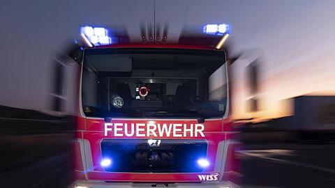 Ein Feuerwehrfahrzeug steht mit eingeschaltetem Blaulicht auf einer Straße.