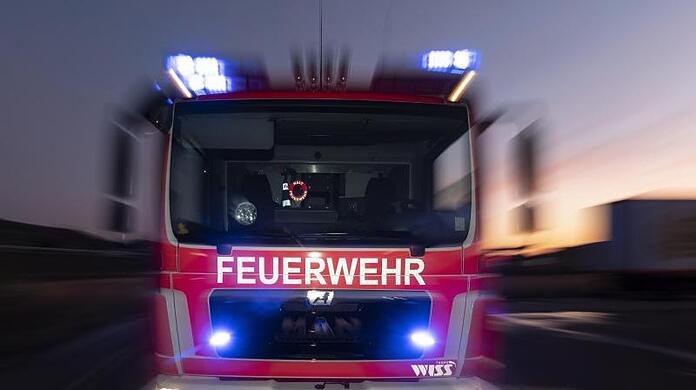 Ein Feuerwehrfahrzeug steht mit eingeschaltetem Blaulicht auf einer Straße.