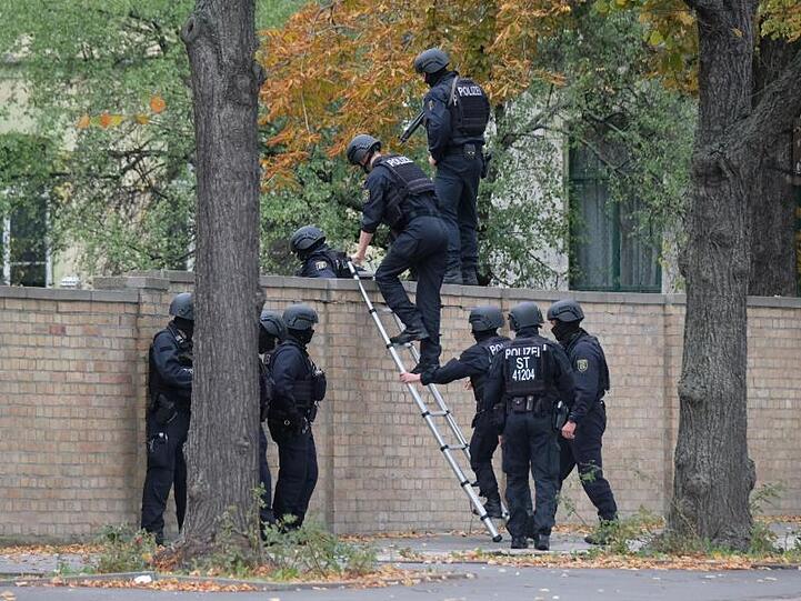 Einsatz in Halle: Polizisten mit Schutzhelmen übersteigen eine Mauer.