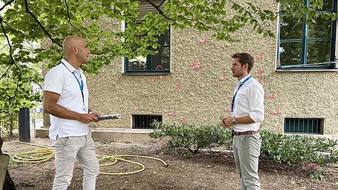 LKA-Beamte Alexander Groß und Fabian Puchelt neben einer 15 Meter hohen Rotbuche, wo Attentäter Emrah I. am Donnerstag von Polizeikugeln getroffen zusammengebrochen ist. Im Hintergrund: Pink markierte Einschusslöcher am Karolinenplatz 4.