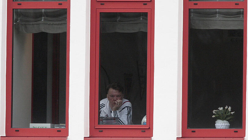 Louis van Gaal blickt aus seinem Bürofenster den Profis beim Auslaufen zu.