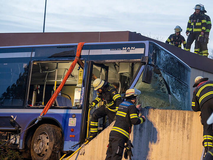 31.01.2026, Bayern, M&uuml;nchen: Feuerwehrleute stehen neben einem verungl&uuml;ckten Linienbus. Bei dem Unfall kam eine Person ums Leben, mehrere wurden verletzt.