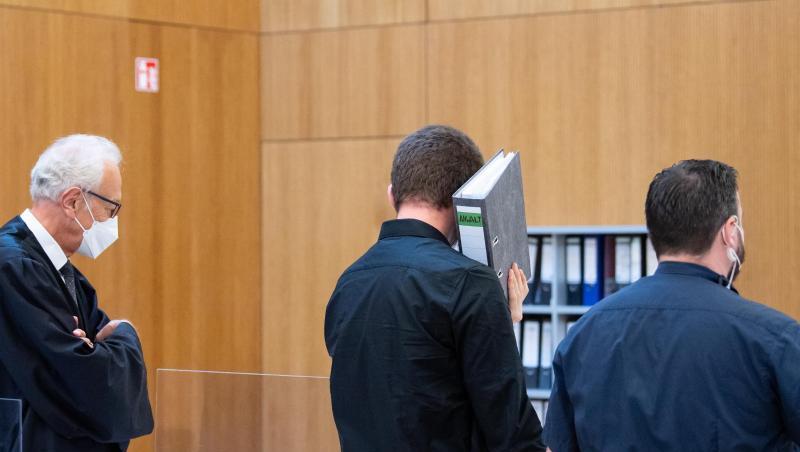 Einer von zwei wegen Mordes angeklagten Männer (M) wird vor Beginn der Verhandlung in den Sitzungssaal geführt. Einer von zwei wegen Mordes angeklagten Männer (M) wird vor Beginn der Verhandlung in den Sitzungssaal geführt.