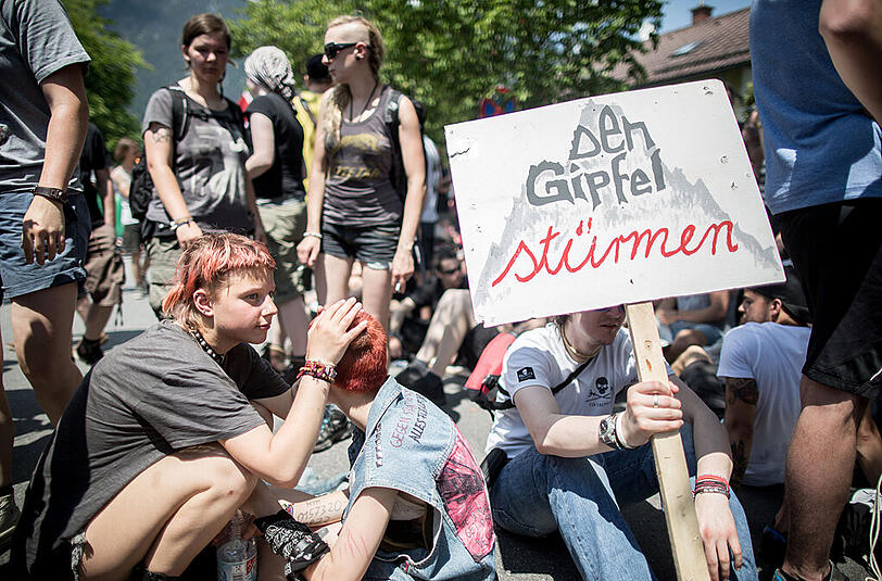 Gegner des G7 Gipfels sitzen mit einem Plakat mit der Aufschrift "Gipfel stürmen" vor dem Marshall Center for European Security Studies