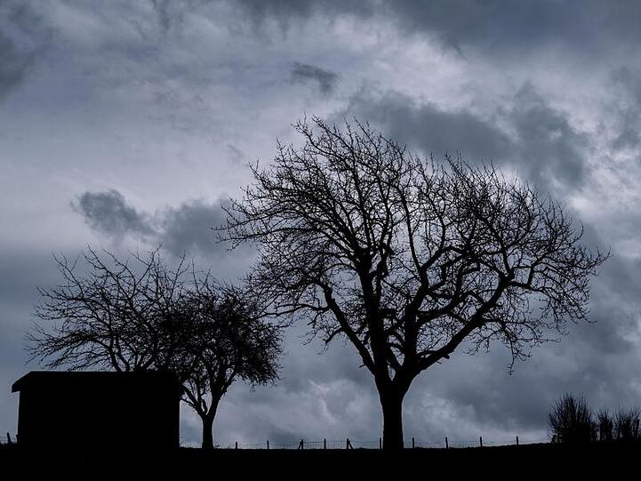 Dunkle Regenwolken sind über einem Feld bei Hattendorf in Niedersachsen zu sehen.