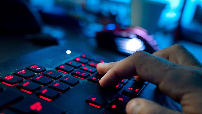 Ein Mann sitzt am Rechner und tippt auf einer Tastatur.