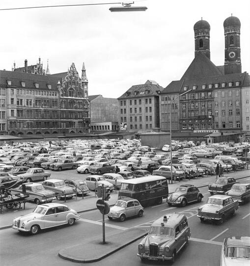 Der Marienhof 1961: ein großer Parkplatz mit reichlich Verkehr drumherum. Bis zum Zweiten Weltkrieg war die Fläche bebaut, die Häuser wurden im Krieg zerstört. Von 1948 bis 1971 wurde hier vor allem geparkt, zu den Olympischen Spielen 1972 entstand das erste Stück Grünfläche.