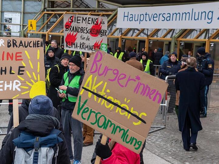Klimaaktivisten demonstrieren mit Plakaten am Haupteingang zu Beginn der Siemens-Hauptversammlung 2020 vor der Olympiahalle. Foto: Peter Kneffel/dpa