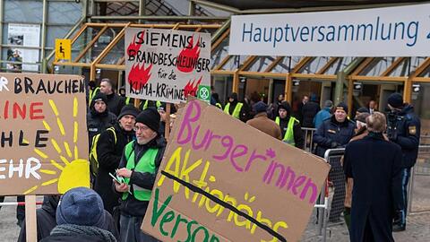 Klimaaktivisten demonstrieren mit Plakaten am Haupteingang zu Beginn der Siemens-Hauptversammlung 2020 vor der Olympiahalle. Foto: Peter Kneffel/dpa
