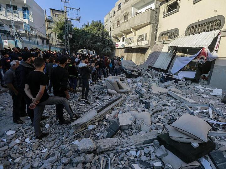 Anwohner und Passanten stehen nach dem israelischen Luftangriff vor dem beschädigten Haus von Baha Abu Al Ata.