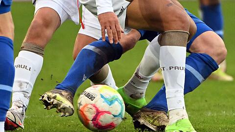 Fußballspieler zweier gegnerischer Mannschaften kämpfen um den Ball.