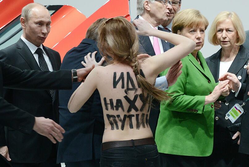 Die Aktivistinnen hatten auf ihren entblößten Oberkörpern große Schriftzüge, die Putin als Dikatatoren bezeichneten. Sie schafften es nahe an die Bundeskanzlerin und den russischen Präsidenten heran, bis die Sicherheitskräfte eingreifen konnten.