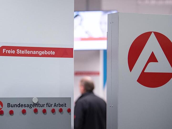 Ein Mann im Wartebereich hinter einer Stellwand für Stellenangebote in Stuttgart.