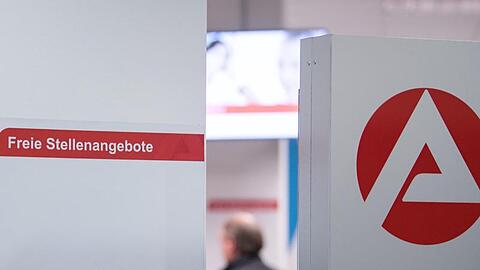 Ein Mann im Wartebereich hinter einer Stellwand für Stellenangebote in Stuttgart.