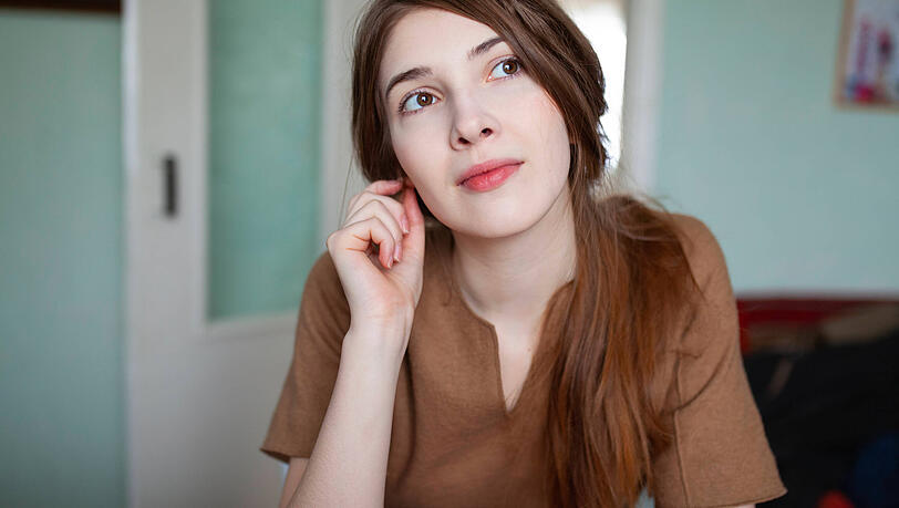 Eine junge Frau in nachdenklicher Pose: Neurowissenschaftler Raphael M. Bonelli warnt davor, zu viel an ChatGPT auszulagern. Dies schw&auml;che das eigene Gehirn.