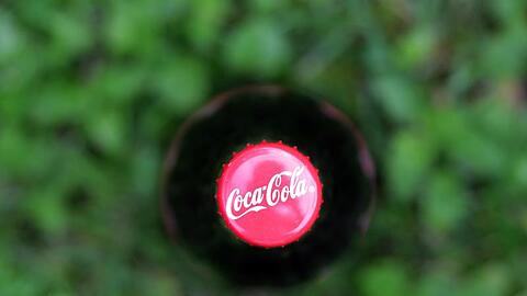 Der Deckel einer Coca Cola Flasche, die auf einer Wiese steht, ist zu sehen. Foto: Karl-Josef Hildenbrand/Archiv