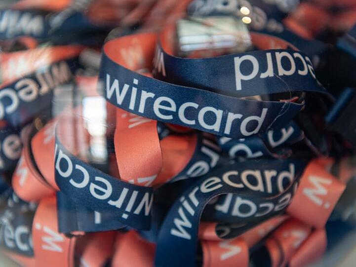 Umhängebändchen mit der Aufschrift "wirecard" liegen während der Wirecard - Hauptversammlung in einem Glasbehälter. Foto: Peter Kneffel/dpa/Archivbild