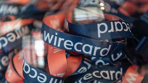 Umhängebändchen mit der Aufschrift "wirecard" liegen während der Wirecard - Hauptversammlung in einem Glasbehälter. Foto: Peter Kneffel/dpa/Archivbild