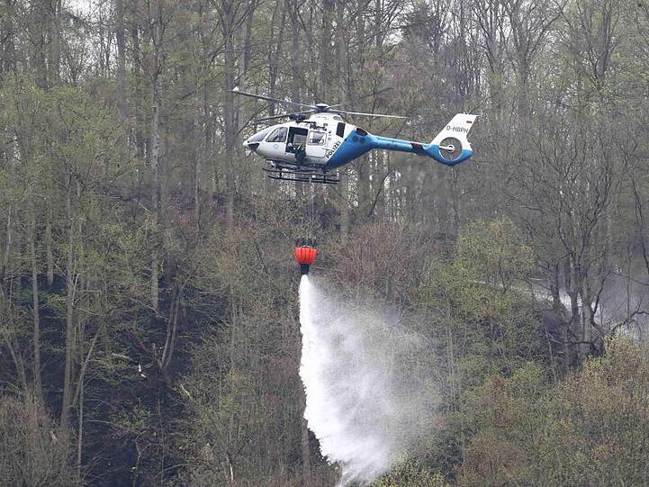 Ein Polizeihubschrauber löscht einen Brand im Wald an der Bleilochtalsperre. Foto: Bodo Schackow/Archivbild