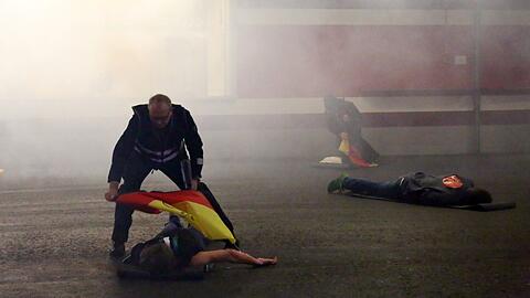 In der Allianz Arena liegen verletzte Fans am Boden, dichte Rauchschwaden vernebeln die Sicht.