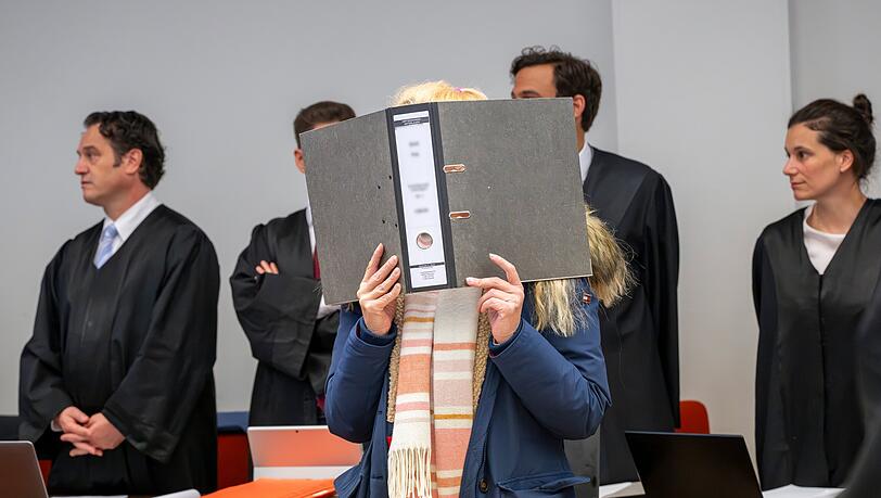 Eine Angeklagte hält im Gerichtssaal des Landgericht II einen Aktenordner vor ihr Gericht. Neben der 58-Jährigen geht es in dem Prozess auch um Vorwürfe gegen ihre Tochter, deren Lebensgefährten und einen Bekannten. Im Raum stehen auch Vorwürfe wegen gewerbsmäßigen Betruges und schwerer Körperverletzung.