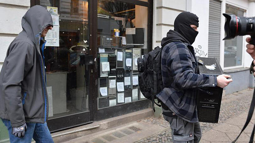 Während einer Razzia bei Reichsbürgern in Berlin trägt ein Polizist einen Computer aus einem Haus im Ortsteil Moabit.