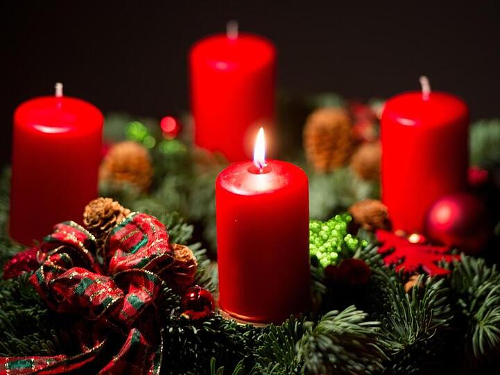Eine Kerze brennt auf einem Adventskranz. Foto: Monika Skolimowska/dpa/Archivblid