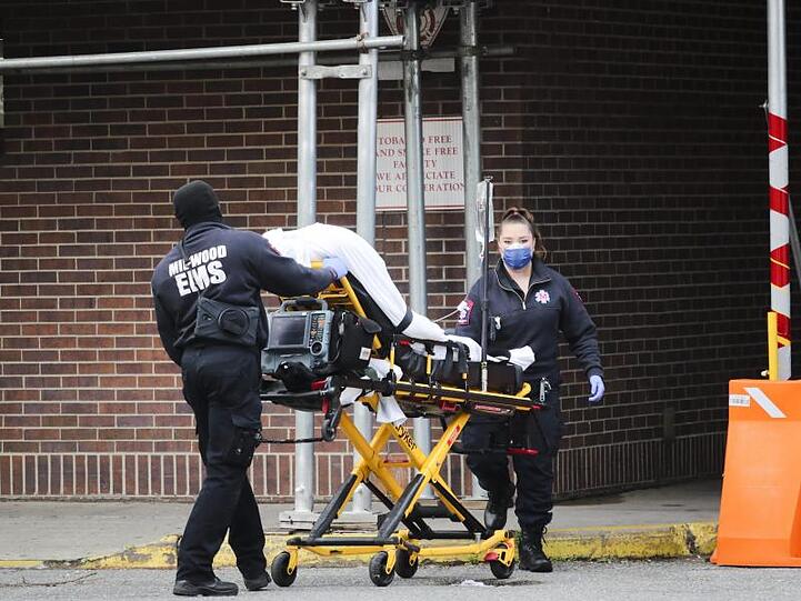 Mitarbeiter des Gesundheitswesens schieben einen Patienten in das Brooklyn Hospital Center in Brooklyn. In der außer Kontrolle geratenen Corona-Pandemie in den USA könnten in den kommenden Monaten nach Modellrechnungen weitere Zehntausende Menschen sterben.