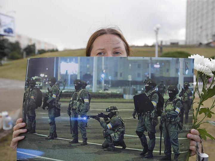Bei einer Demonstration in Minsk präsentiert eine Frau ein Foto der gegen die Protestbewegung eingesetzten Sicherheitskräfte.