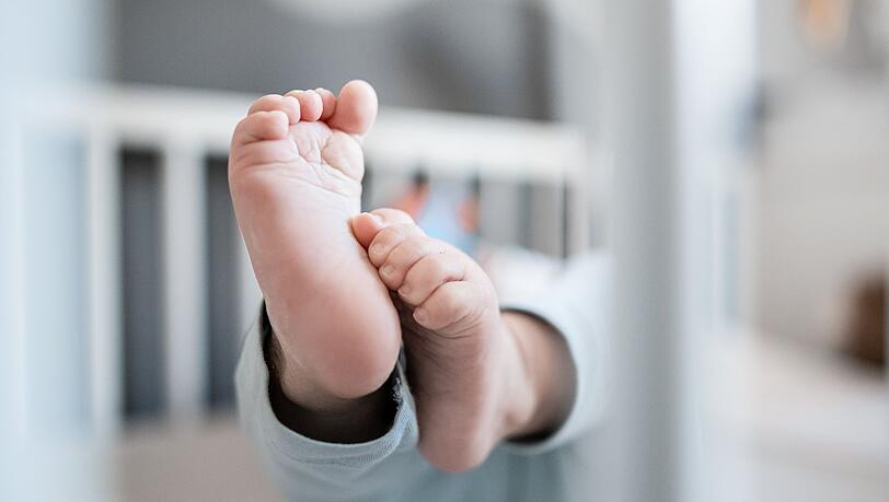 Die Füße eines Babys sind in einem Kinderbett zu sehen.