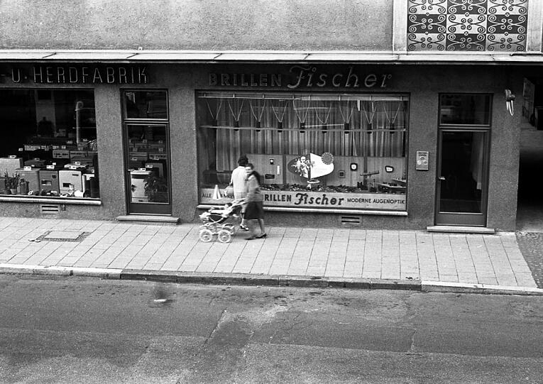 Dachauer Straße 1964: Eine Frau schaut ins Ladenfenster, eine andere schiebt ein Kinderwagerl vorbei.