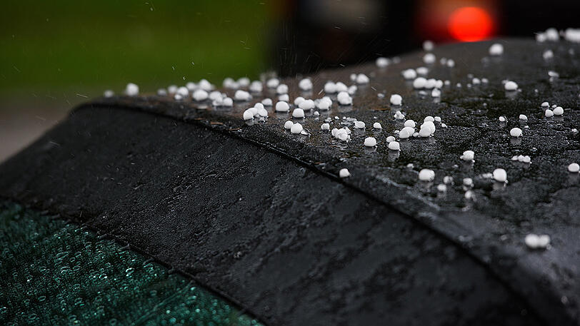 Zentimetergroße Hagelkörner liegen auf der Abdeckung eines Cabriolets in München. Foto: Florian Eckl