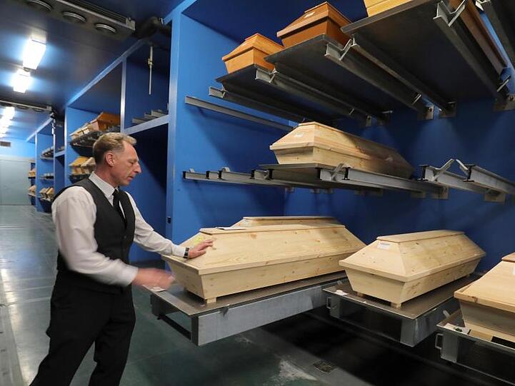 Ein Bestatter geht durch das Sarglager. Foto: Wolfgang Kumm/dpa/Archivbild