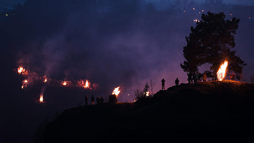Beeindruckende Bilder: Zahlreiche Besucher stehen am Samstag nahe der Burg Pottenstein in der Stadt Pottenstein und blicken auf hunderte Bergfeuer. Grund ist das katholische Fest der Ewigen Anbetung.