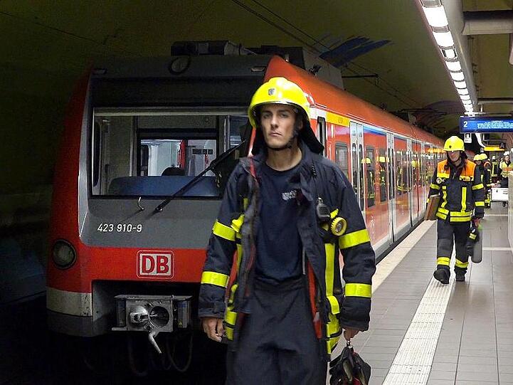 Feuerwehrleute gehen an einer S-Bahn in der Frankfurter Bahnstation Ostendstraße vorbei, wo es zu dem tödlichen Unfall kam.