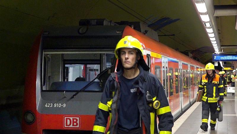 Feuerwehrleute gehen an einer S-Bahn in der Frankfurter Bahnstation Ostendstraße vorbei, wo es zu dem tödlichen Unfall kam.