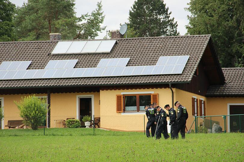 Über diese Wiese, auf der hier Polizisten nach Spuren suchen, sind die Täter offenbar zum Haus des Ehepaars gelangt.
