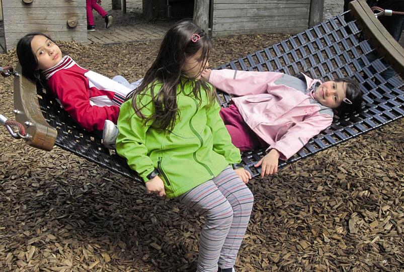 Drei Mädchen auf der Hängematte auf dem Neuaubinger Spielplatz.