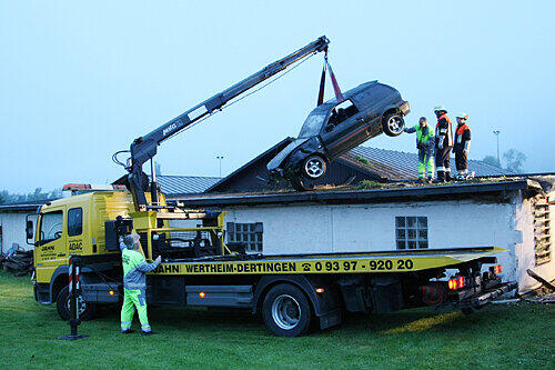Ein Laster mit Kran hebt das Auto wieder vom Dach. Der Wagen ist nach dem spektakulären Stunt wohl bloß noch Schrott.