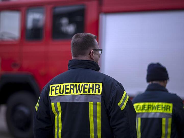 Feuerwehrmänner stehen vor einem Feuerwehrauto. Foto: Jens Büttner/zb/dpa/Archiv