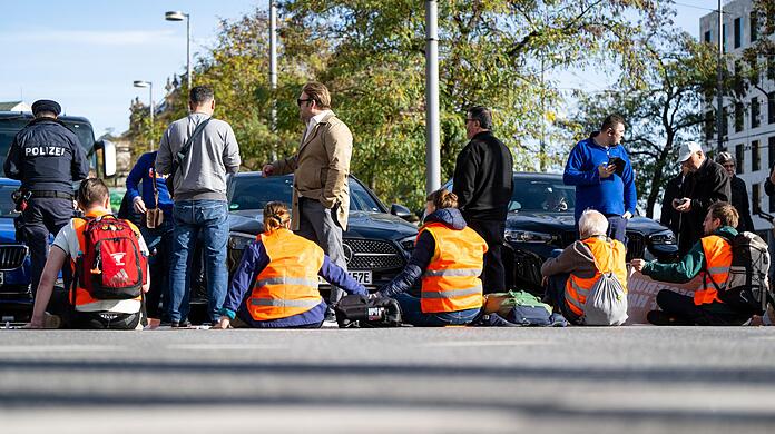 Klimaaktivisten haben sich am Karlsplatz in der Münchner Innenstadt auf die Fahrbahn geklebt und blockieren die Straße.