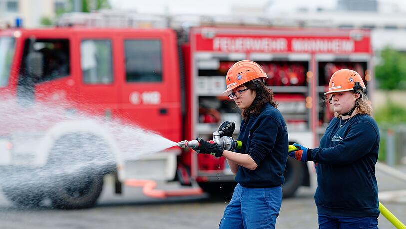 Ilias (links) und Annabella, Mitglieder der Jugendfeuerwehr in Mannheim, halten bei einer &Uuml;bung einen Feuerwehrschlauch in den H&auml;nden.