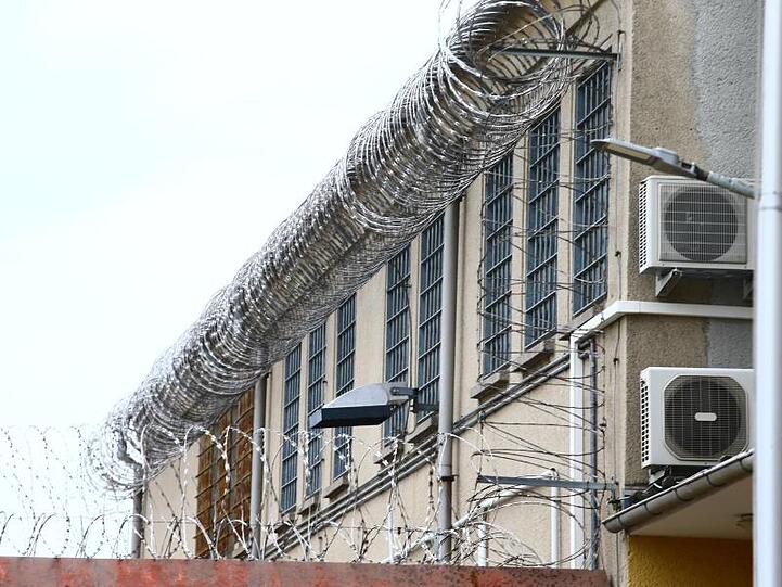 Stacheldraht und vergitterte Fenster umzeunen ein Gefängnis. Foto: Bodo Schackow/dpa-Zentralbild/dpa/Symbolbild