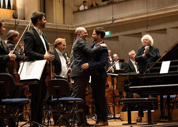 Im Herkulessaal umarmt der Komponist Francisco Coll den Pianisten Kirill Gerstein, der eben sein Klavierkonzert uraufgef&uuml;hrt hat. Dirigent Simon Rattle goutiert&rsquo;s.