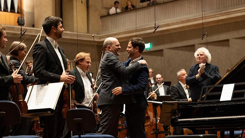 Im Herkulessaal umarmt der Komponist Francisco Coll den Pianisten Kirill Gerstein, der eben sein Klavierkonzert uraufgef&uuml;hrt hat. Dirigent Simon Rattle goutiert&rsquo;s.
