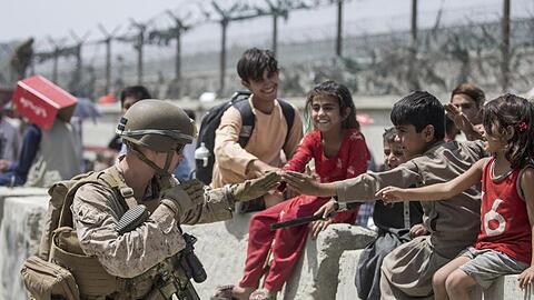 Ein US-Marine spielt mit Kindern, die während der Evakuierung am Hamid Karzai International Airport warten.