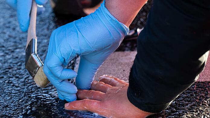 Ein Polizisten löst die Verklebung, mit der sich ein Klimaaktivist der Umweltschutzbewegung "Letzte Generation" geklebt hatte.